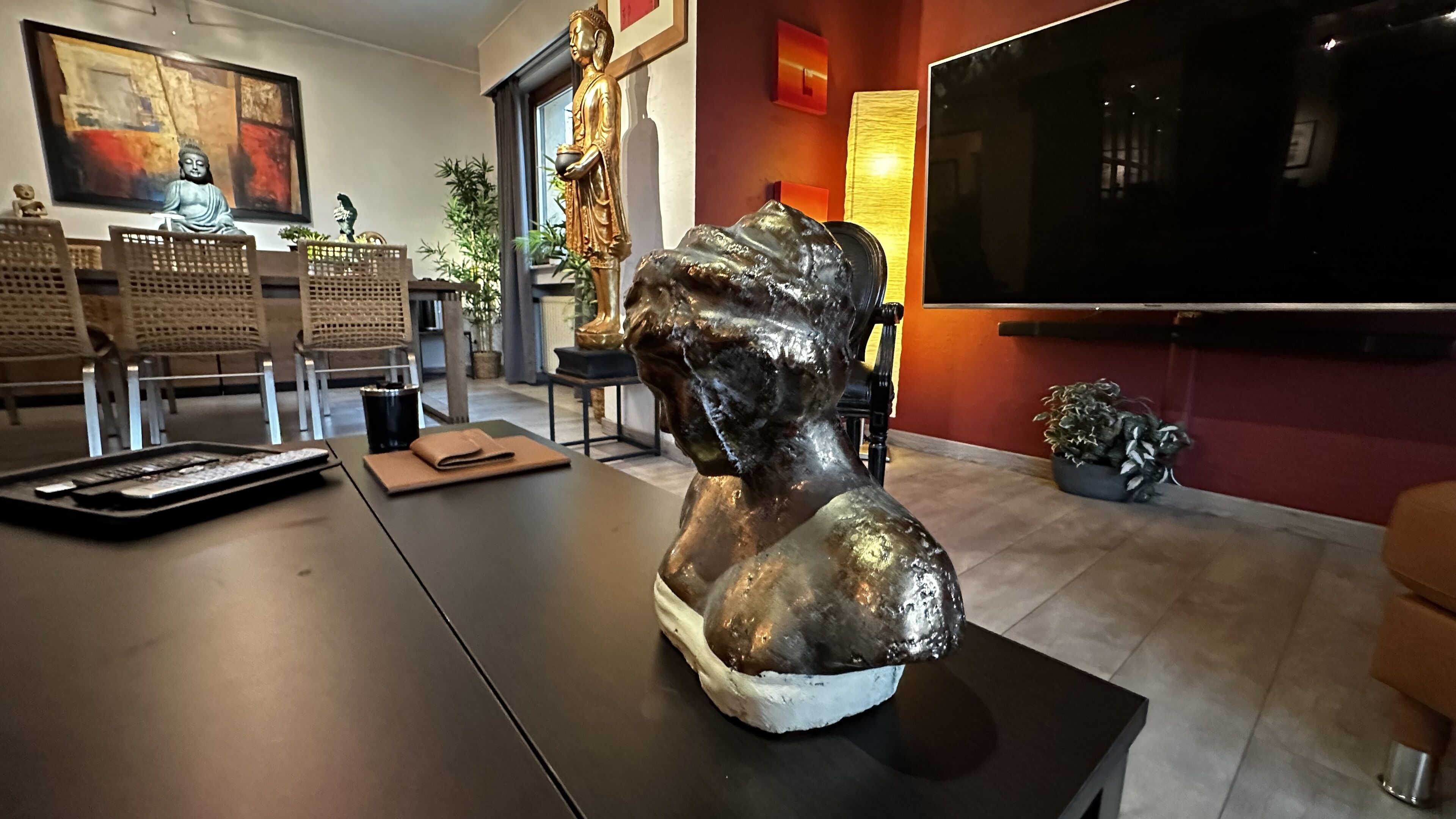 Una sala de estar con un sofá, una mesa de centro, un televisor y una estatua de Buda.
