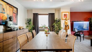 Comedor moderno con una mesa de madera, sillas de mimbre y una estatua de Buda a la izquierda.