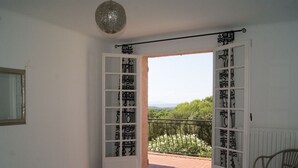 Une chambre avec un grand lit, une vue sur l’extérieur et un balcon doté d’une balustrade.