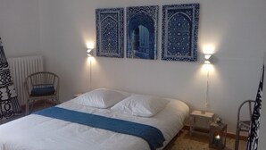 Une chambre à coucher avec un lit, une chaise et deux lampes fixées au mur.