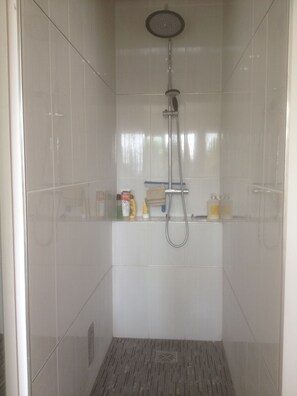 Enjoy a refreshing shower with a handheld showerhead and wall-mounted faucet in this shower stall.