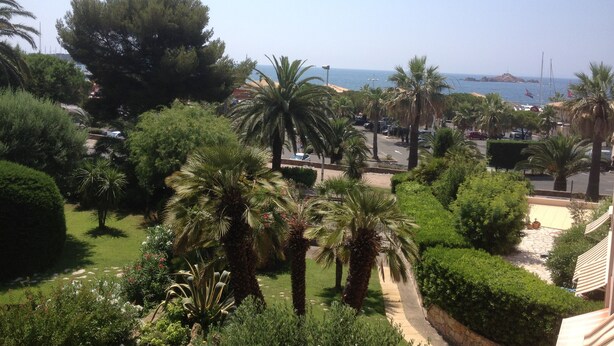 A coastal view with palm trees, a pathway, and a beach in the background. - Charming apartment in property with pool and large park (Saint-Raphaël)