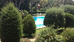 A swimming pool surrounded by lush greenery and trees. - Charming apartment in property with pool and large park (Saint-Raphaël)