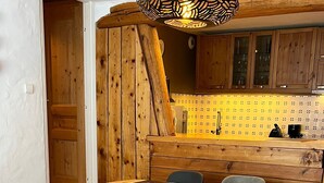 Een gezellig eetgedeelte met een houten tafel en stoelen, een klein rond tafeltje en een rode stoel.