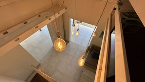 Ein Zimmer mit hoher Decke, freiliegenden Lüftungsrohren und hängenden Pendelleuchten.