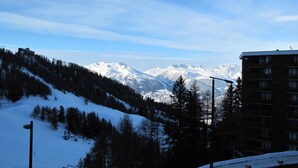 A snow-covered mountain landscape with a building in the foreground. - Charming apartment in La Plagne with equipped kitchen and quick access to the slopes (La Plagne)