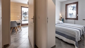 A bedroom with a bed, a window with a view, and a door leading to a dining area. - Charming apartment in La Plagne with equipped kitchen and quick access to the slopes (La Plagne)