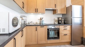 A modern kitchen with wooden cabinets, a stainless steel refrigerator, a built-in oven, and a coffee maker. - Charming apartment in La Plagne with equipped kitchen and quick access to the slopes (La Plagne)