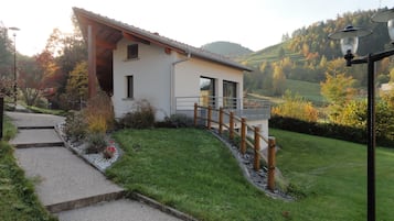 Une maison moderne avec un toit en pente, une terrasse en bois et un chemin pavé menant à l’entrée.