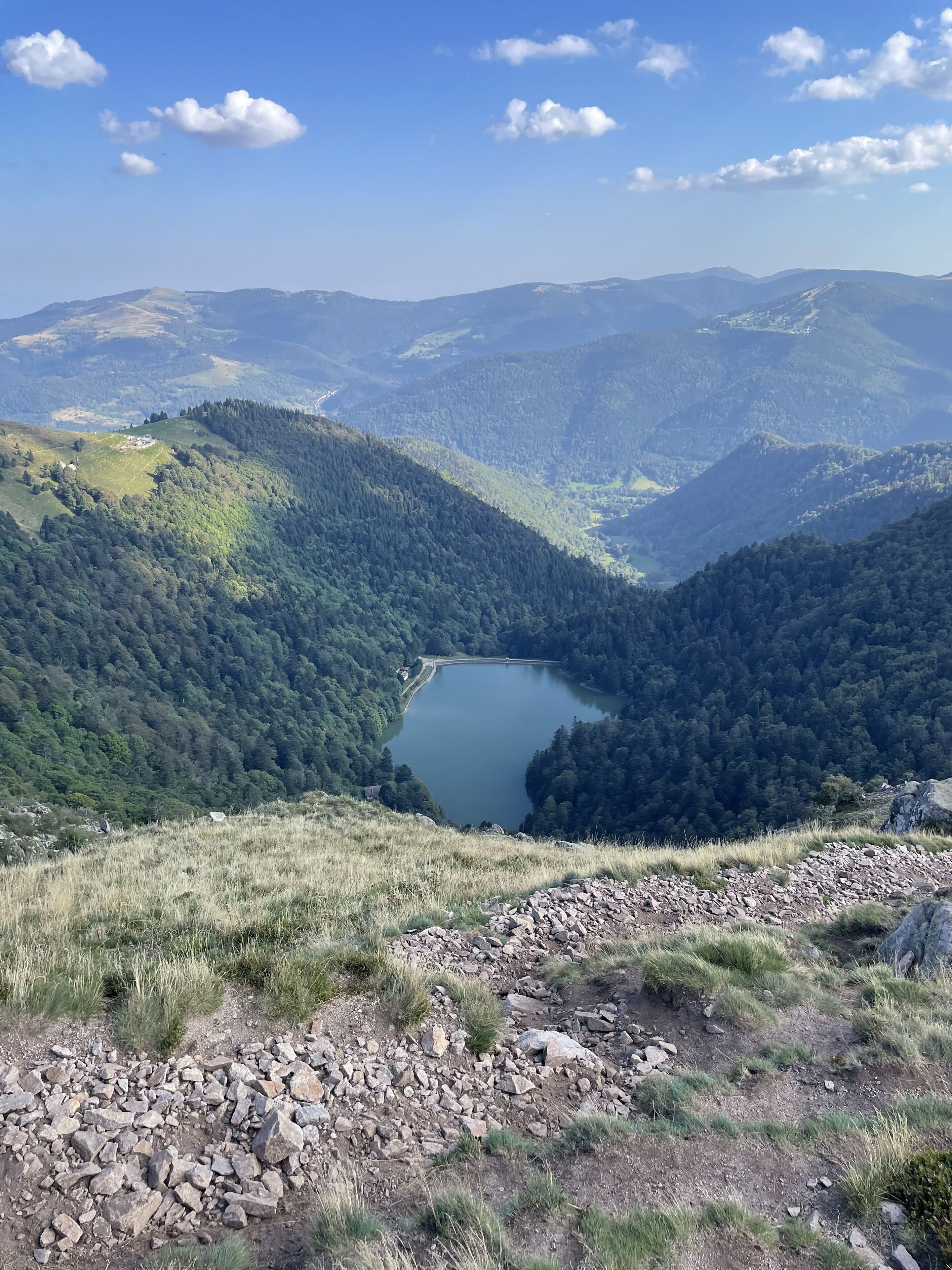 A mountainous landscape with a lake and a small building on a hill.