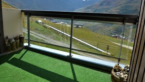 Un balcon offrant une vue dégagée sur un paysage montagneux, une zone herbeuse et une route.