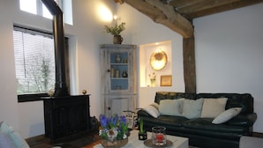 Ein Wohnzimmer mit Kamin, einer schwarzen Ledersofa, einem weißen Sessel und einem weißen Couchtisch mit Blumenarrangement.