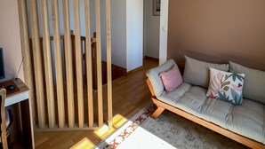 Ett modernt vardagsrum med en vägg av trä, en soffa med dekorativa kuddar och en mönstrad matta.