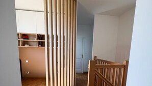 En hall med trägolv, en vit dörr och en delvis öppen trävägg.