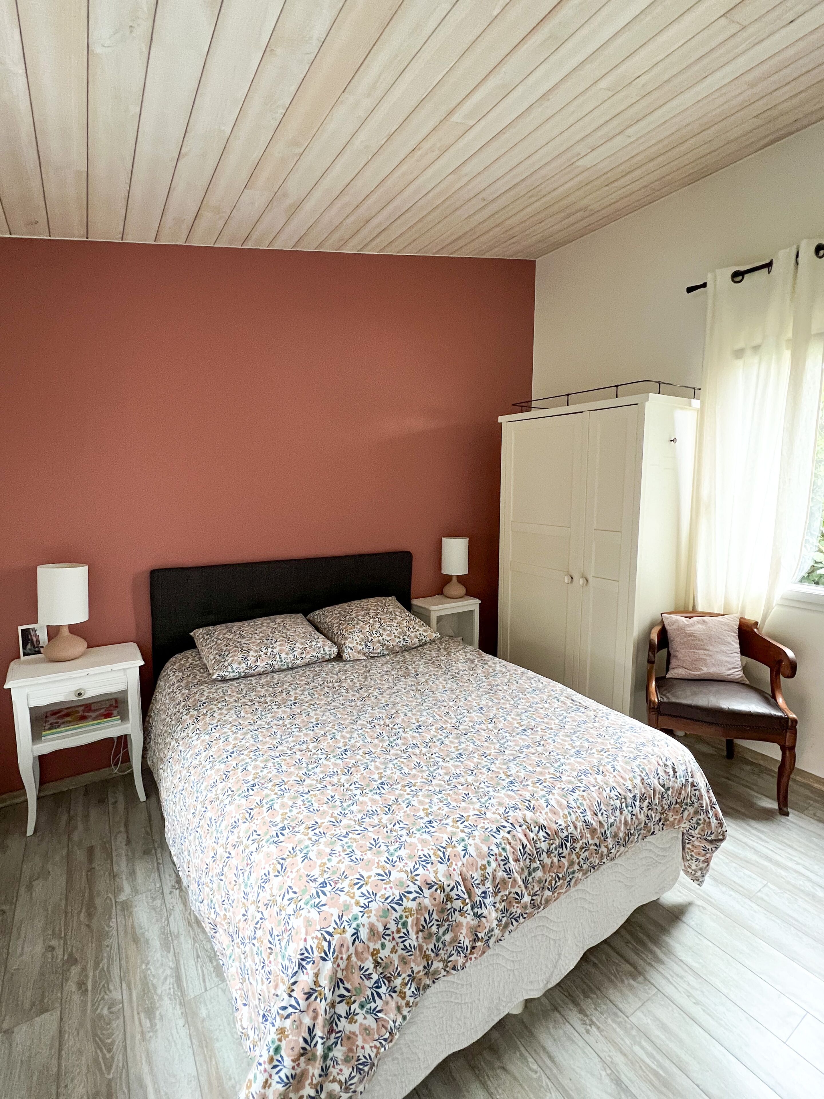 A bedroom with a bed, nightstands, a wardrobe, and a chair.