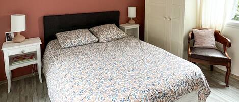 A bedroom with a bed, nightstands, a wardrobe, and a chair.