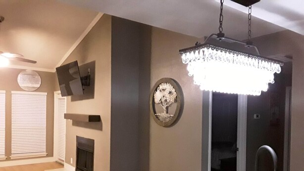 Una cucina moderna con un piano di lavoro in marmo, un lampadario, un camino e un'area pranzo con tavolo e sedie.