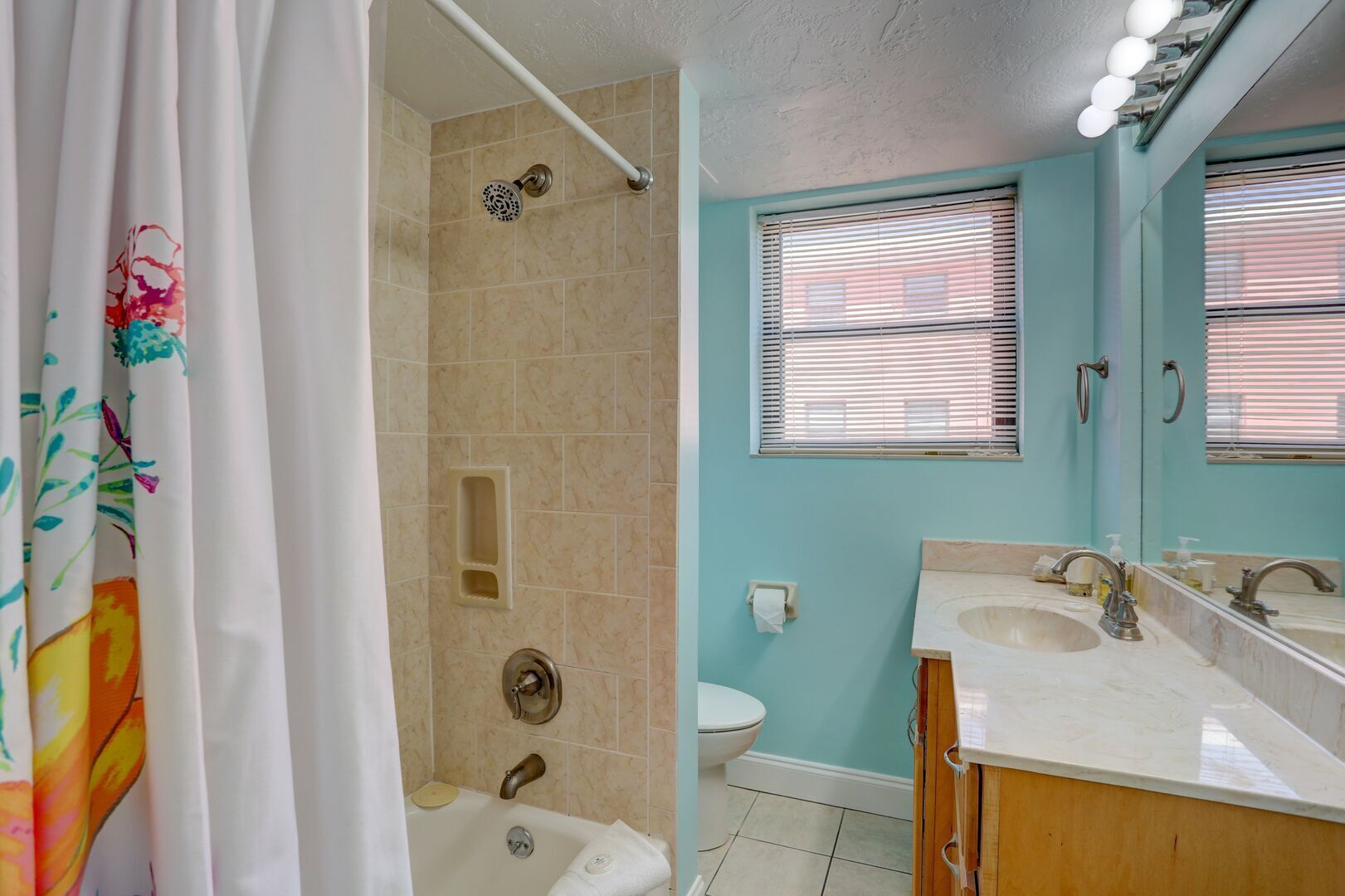Een badkamer met een douche, toilet en twee wastafels met spiegels.