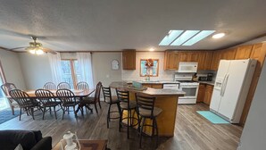 Una cocina amplia con armarios de madera, una isla central y un comedor con mesa y sillas.
