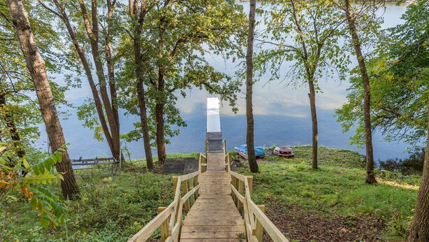 Una escalera de madera que conduce a un muelle junto a un lago, rodeado de árboles.