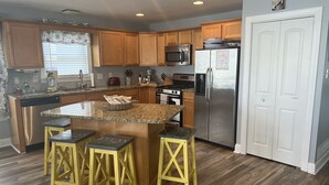 A modern kitchen with wooden cabinets, a stainless steel refrigerator, and a granite countertop.