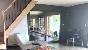 A spacious living area with a staircase, a round glass table, and a sofa. - PROMO FINISTERE SUD Villa sea view POOL /SPA indoor, heated (Plouhinec)