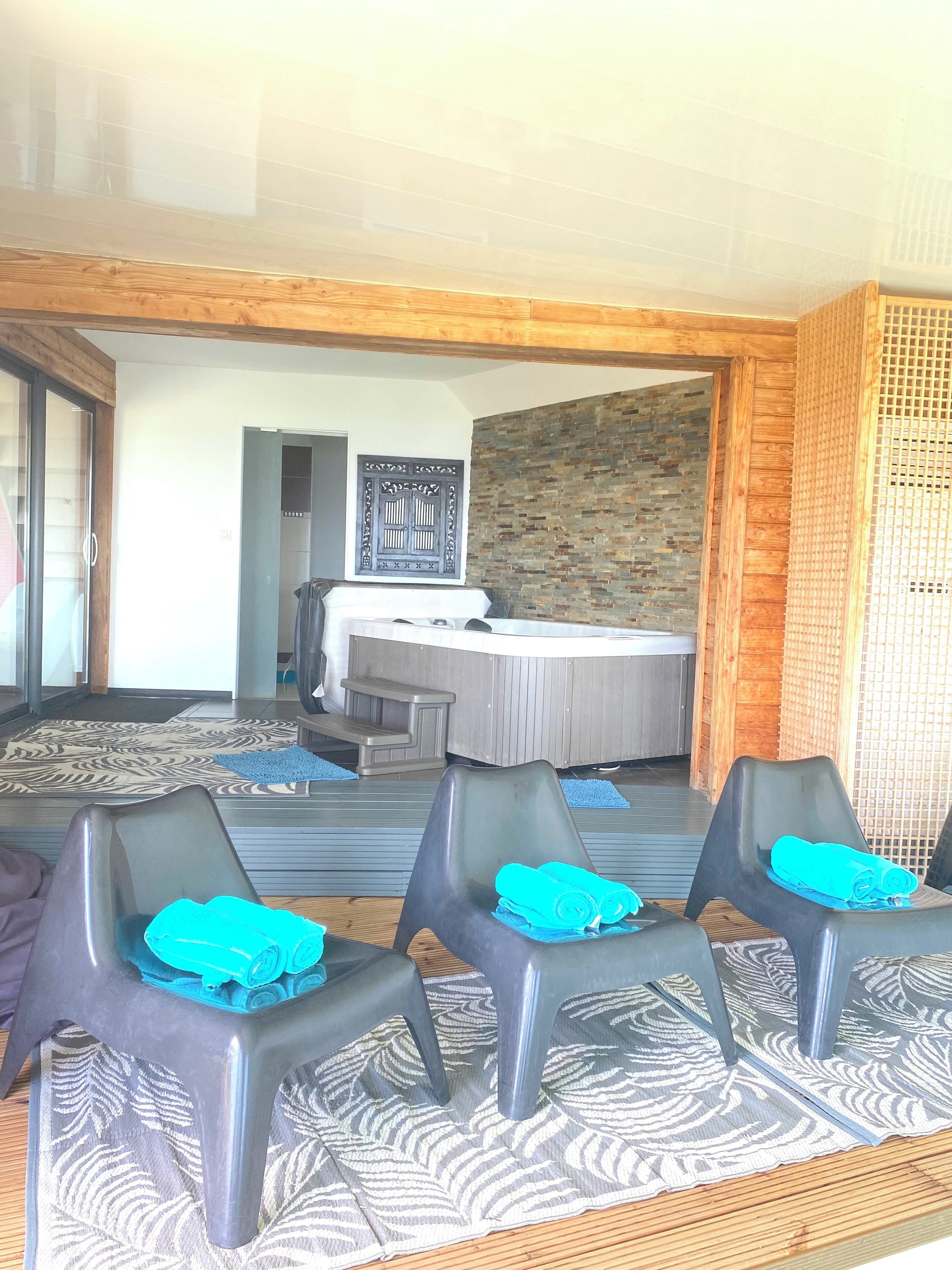 Une pièce avec un plafond en bois, un tapis à motifs, une table de massage et deux chaises recouvertes de serviettes bleues.