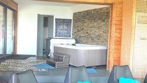 A room with a wooden ceiling, a patterned rug, a massage table, and two chairs with blue towels. - PROMO FINISTERE SUD Villa sea view POOL /SPA indoor, heated (Plouhinec)