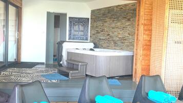 Une pièce avec un plafond en bois, un tapis à motifs, une table de massage et deux chaises recouvertes de serviettes bleues.