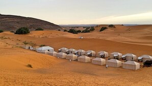 A desert landscape with multiple tents arranged in a row, suggesting a caravan or camping site. - 3- Sweet Erg Chebbi Merzouga (Merzouga)