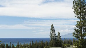 A coastal property with multiple buildings, a clear view of the ocean, and a mountain in the distance.