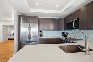 Una cocina moderna con un refrigerador de acero inoxidable, un microondas y un lavamanos con un grifo moderno.