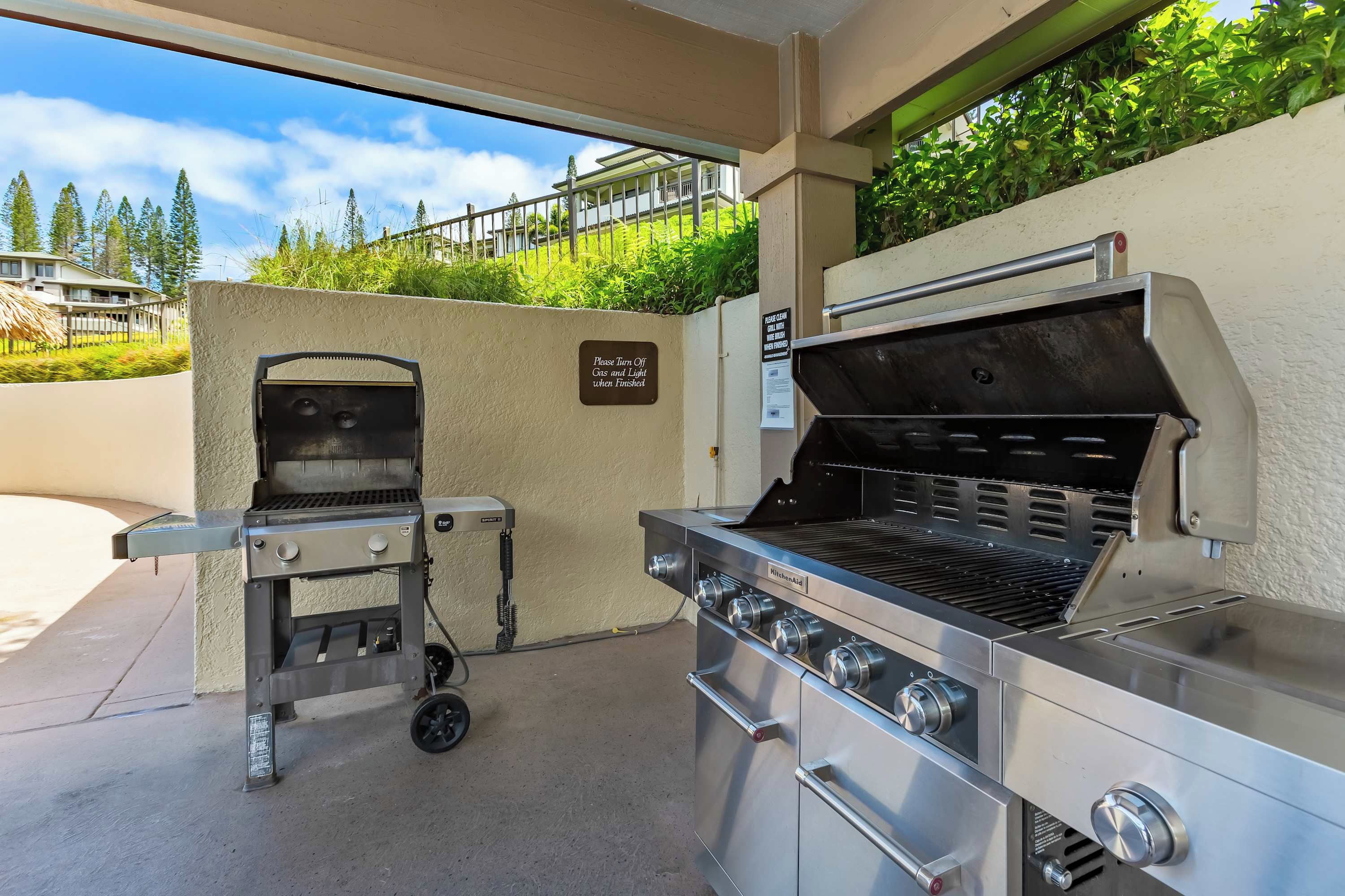 Een buitenbarbecueplaats met een ingebouwde barbecue en een apart grillstation, beide met meerdere branders en bedieningsknoppen.