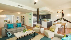 A modern living room with a sofa, coffee table, and a dining area with chairs.