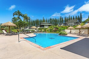 A swimming pool with lounge chairs and umbrellas, surrounded by greenery and buildings. - Luxury Golf Villa in Kapalua Maui with Ocean and Sunset Views (Kapalua)