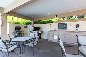An outdoor patio with a grill, seating, and a sign detailing pool rules. - Luxury Golf Villa in Kapalua Maui with Ocean and Sunset Views (Kapalua)