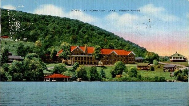 Un hotel en Mountain Lake, Virginia, con un edificio grande y construcciones más pequeñas, rodeado de abundante vegetación y un cuerpo de agua.