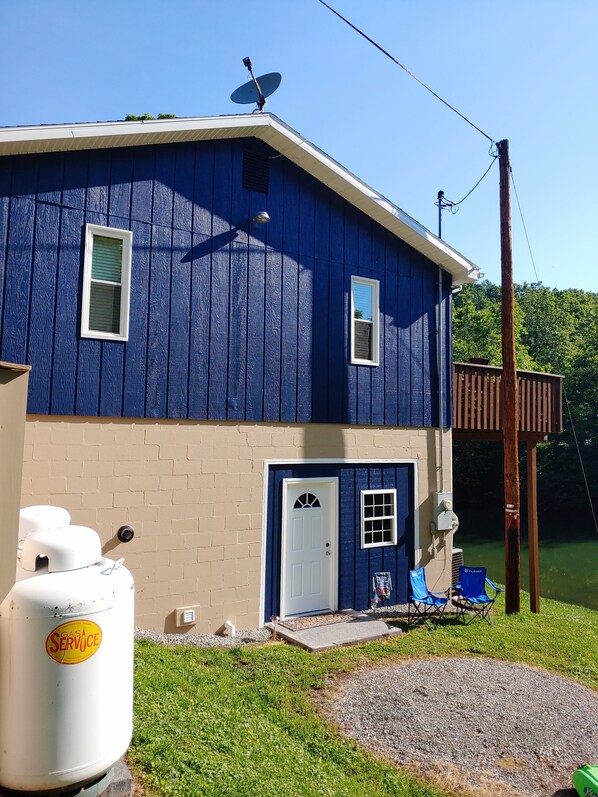 A two-story house with a blue exterior, a front door, and a small porch with chairs.