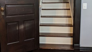 A wooden door with a brass doorknob, a white staircase with wooden steps, and a window above the door. - *CLOSED FOR 2026 SEASON* Schmidt Farm: an interactive farm experience (Preston)