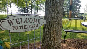 A metal sign with the text "WELCOME TO THE FARM" mounted on a fence. - *CLOSED FOR 2026 SEASON* Schmidt Farm: an interactive farm experience (Preston)