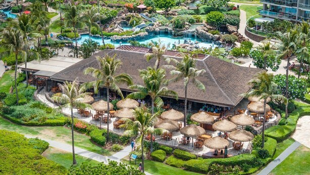 A resort with a large pool, outdoor seating areas, and lush landscaping.