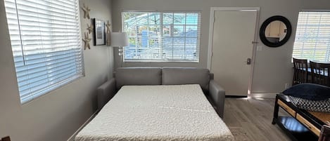 Un dormitorio con una cama, una mesa redonda, un sofá y un ventilador de techo.