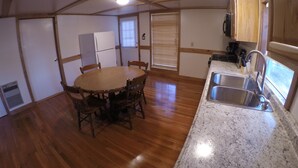 Una cocina compacta con una mesa de comedor de madera, un lavamanos empotrado y armarios de madera.