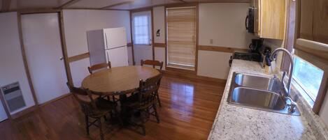 Una cocina compacta con una mesa de comedor de madera, un lavamanos empotrado y armarios de madera.