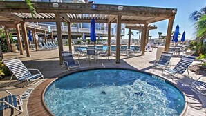 Un área de piscina con sillones de descanso y una pérgola de madera.