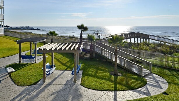 Un paseo marítimo con un mirador, bancos y una terraza de madera con vistas al mar.