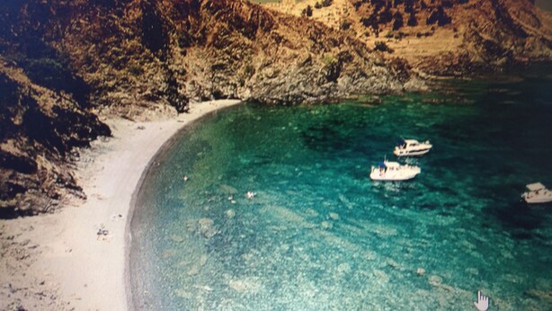 Una platja amb aigua turquesa cristal·lina i un vaixell.
