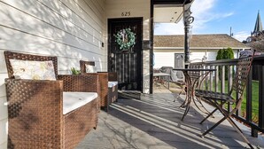 A porch with wicker furniture, a black door, and a number 625 on the wall. - Just off 6th Ave!  Beautifully Renovated Home! Close to UPS. (Tacoma)