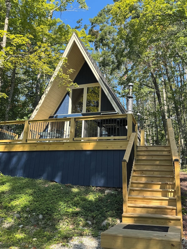 A cabin with a wooden deck, a staircase, and a chimney.