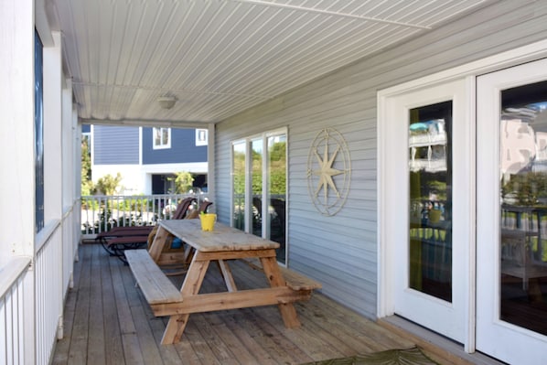 A covered porch with wooden picnic tables and a large sliding glass door.